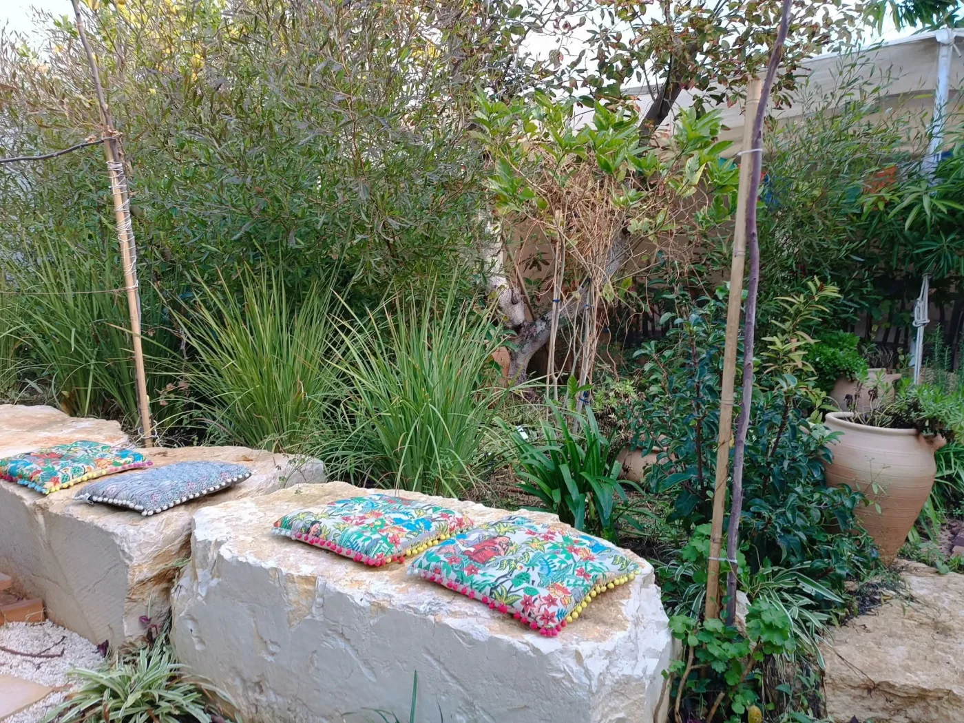 ספסל אבן עם כריות צבעוניות בגינה